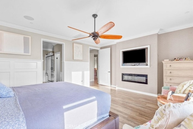 bedroom featuring baseboards, a glass covered fireplace, ceiling fan, ornamental molding, and light wood-type flooring