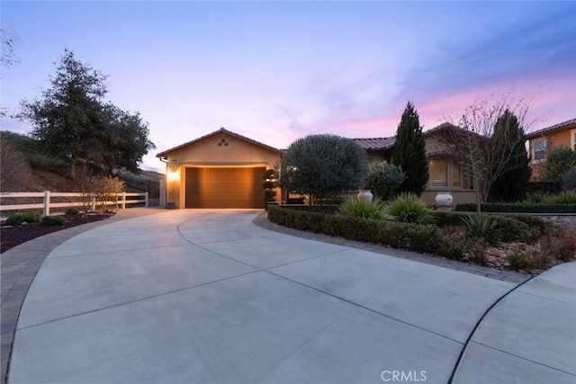 view of front of property featuring an attached garage, fence, concrete driveway, and stucco siding