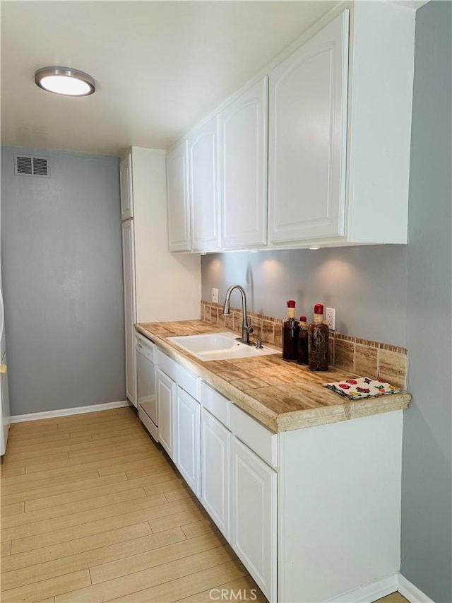 kitchen featuring sink, white cabinets, white dishwasher, and light hardwood / wood-style floors