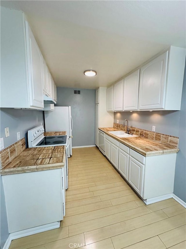 kitchen featuring white cabinetry, sink, white appliances, and light hardwood / wood-style floors