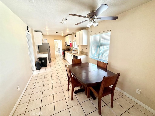 tiled dining space featuring ceiling fan, sink, and a textured ceiling