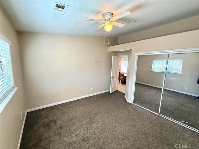 unfurnished bedroom with dark carpet, a closet, and ceiling fan