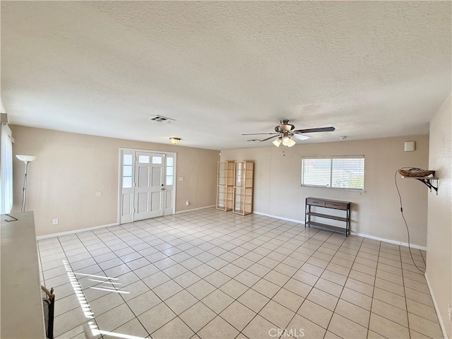 tiled empty room featuring ceiling fan and a textured ceiling