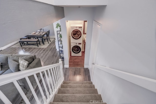 stairs with stacked washer and dryer and wood-type flooring