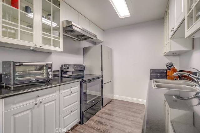 kitchen featuring black electric range oven, sink, light hardwood / wood-style flooring, white cabinetry, and dark stone countertops