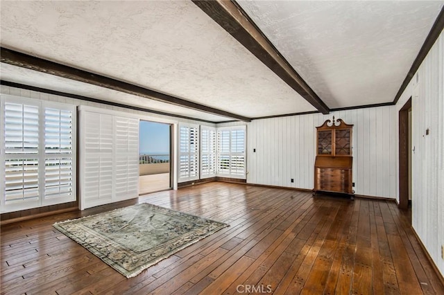 unfurnished living room featuring hardwood / wood-style flooring, beam ceiling, and a textured ceiling