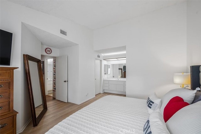 bedroom featuring ensuite bath and light hardwood / wood-style floors