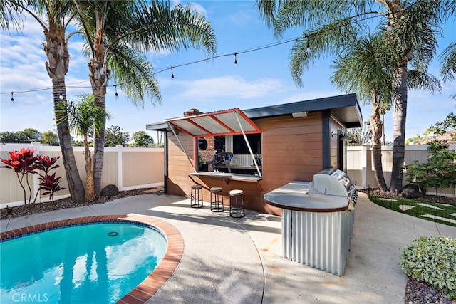 rear view of property featuring a bar, a fenced in pool, and a patio