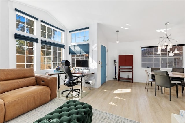 home office with plenty of natural light, high vaulted ceiling, a notable chandelier, and light hardwood / wood-style floors