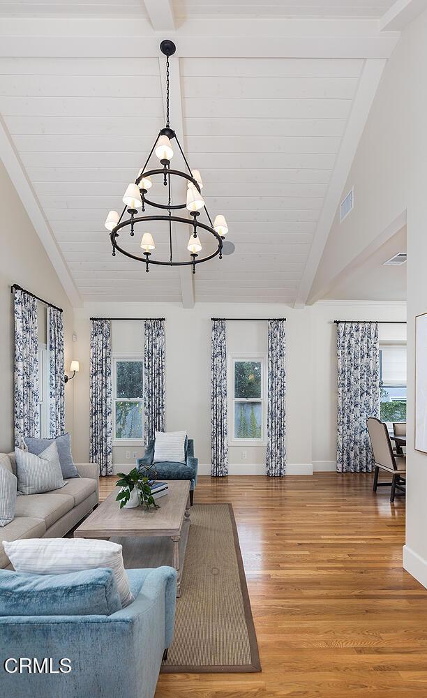 living room with hardwood / wood-style floors, high vaulted ceiling, beamed ceiling, and a chandelier