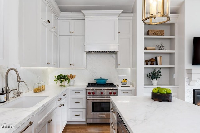 kitchen with sink, white cabinetry, light stone countertops, and premium range