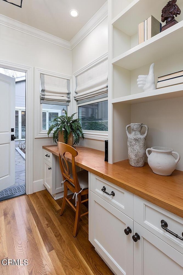 office space featuring light hardwood / wood-style floors, crown molding, and built in desk