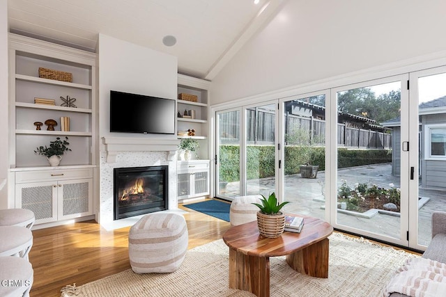 sunroom with hardwood / wood-style floors, high vaulted ceiling, and built in shelves