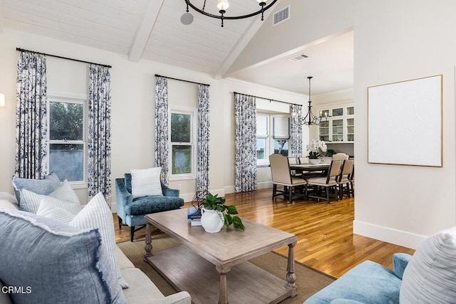 living room featuring hardwood / wood-style floors, vaulted ceiling with beams, and a notable chandelier