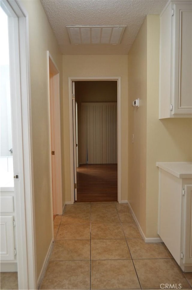 hallway featuring light tile patterned floors and a textured ceiling