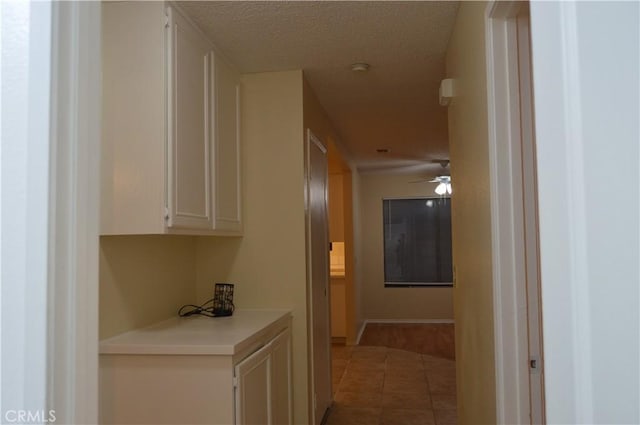 hallway featuring tile patterned floors and a textured ceiling