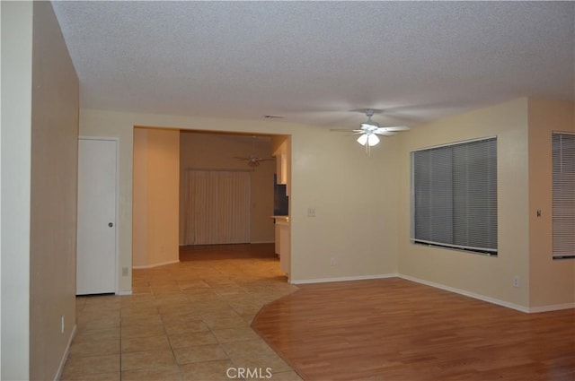 unfurnished room with ceiling fan, light hardwood / wood-style floors, and a textured ceiling