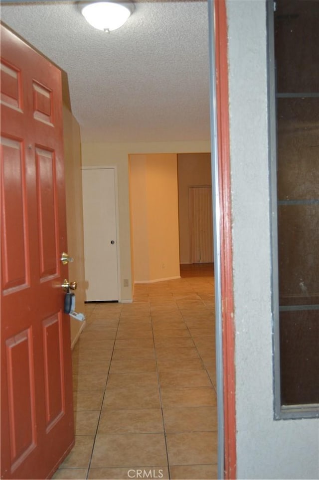 hallway featuring tile patterned flooring and a textured ceiling