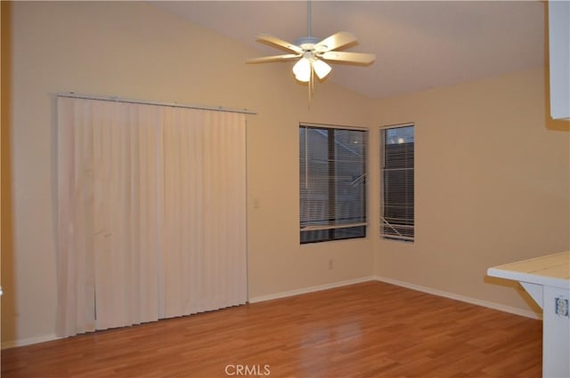 spare room featuring lofted ceiling, ceiling fan, and light wood-type flooring