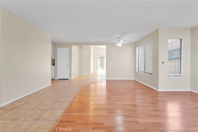 spare room featuring light tile patterned flooring, ceiling fan, a textured ceiling, and baseboards