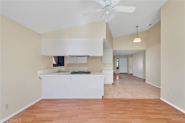 kitchen featuring a peninsula, light countertops, white cabinets, and pendant lighting