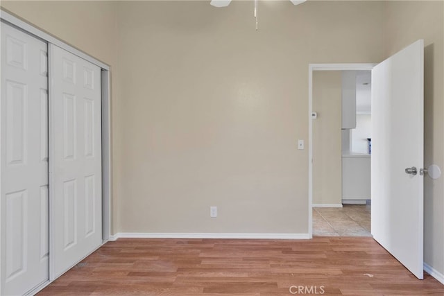 unfurnished bedroom with a closet, light wood-style flooring, and baseboards