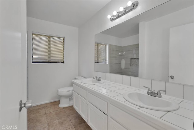 bathroom with a sink, a tile shower, toilet, and double vanity