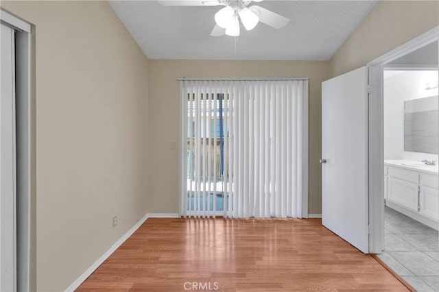 interior space featuring ensuite bath, light wood-type flooring, a sink, and baseboards