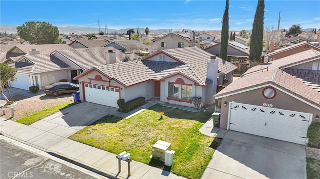 view of front of property featuring a garage, concrete driveway, a residential view, a tiled roof, and a front yard