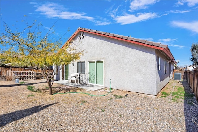 rear view of house with a fenced backyard, a tiled roof, a patio, and stucco siding