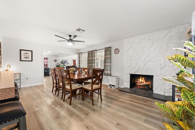 26639 Chambers Ave, Menifee, CA 92586 - dining room with visible vents, baseboards, a stone fireplace, a ceiling fan, and light wood-style flooring