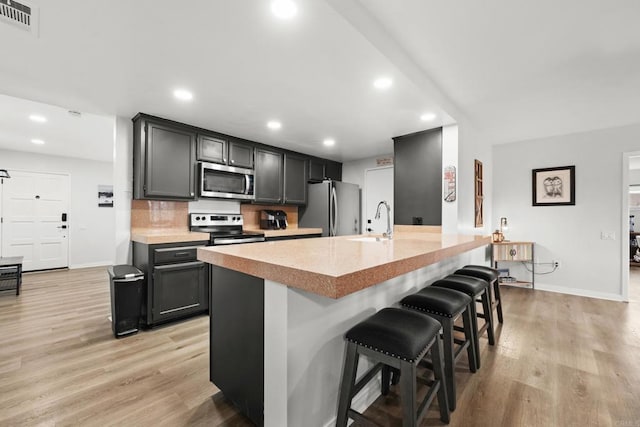 26639 Chambers Ave, Menifee, CA 92586 - kitchen featuring appliances with stainless steel finishes, light wood-style floors, a breakfast bar area, baseboards, and visible vents