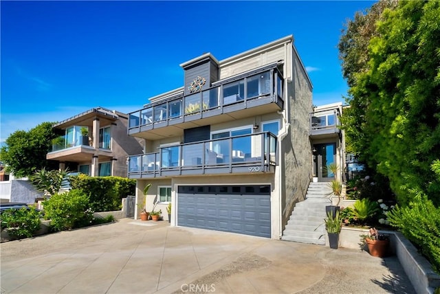 920 Quivera St, Laguna Beach, CA 92651 - modern home with concrete driveway, an attached garage, a balcony, stucco siding, and stairs