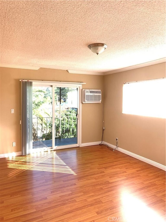 empty room featuring hardwood / wood-style flooring, crown molding, and a wall mounted AC