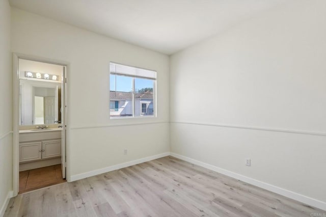 unfurnished bedroom featuring ensuite bathroom, sink, and light hardwood / wood-style flooring