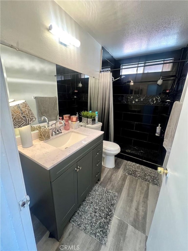 bathroom with hardwood / wood-style flooring, vanity, a textured ceiling, toilet, and walk in shower