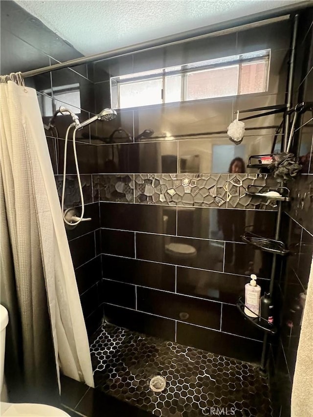 bathroom featuring curtained shower, toilet, and a textured ceiling