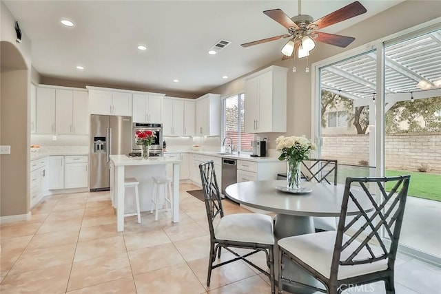 interior space featuring appliances with stainless steel finishes, a kitchen island, sink, and white cabinets