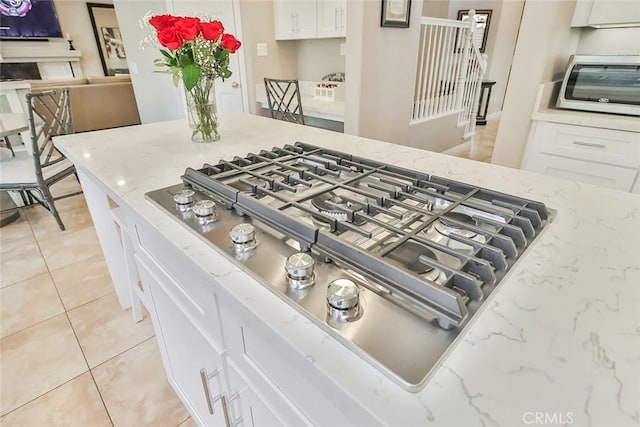 interior details featuring white cabinetry, light stone countertops, and stainless steel gas stovetop