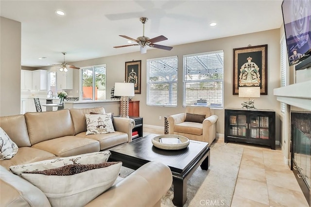 tiled living room featuring ceiling fan and a large fireplace