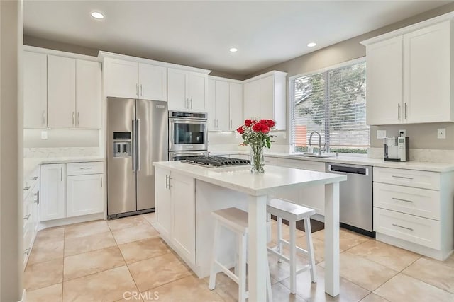 kitchen featuring stainless steel appliances, white cabinets, a center island, light tile patterned floors, and sink