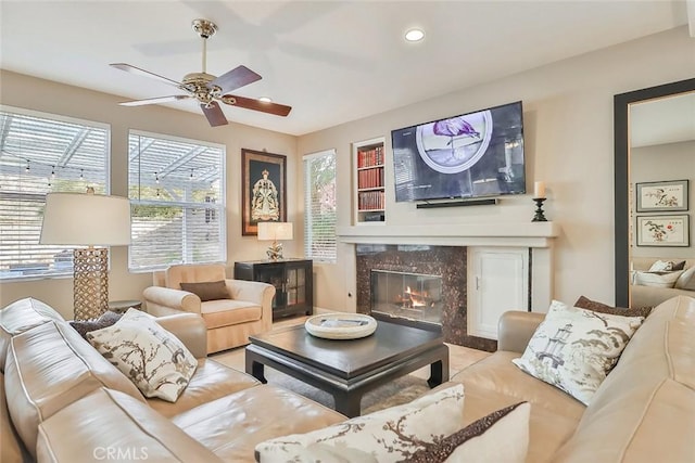 living room with ceiling fan, a high end fireplace, and a healthy amount of sunlight