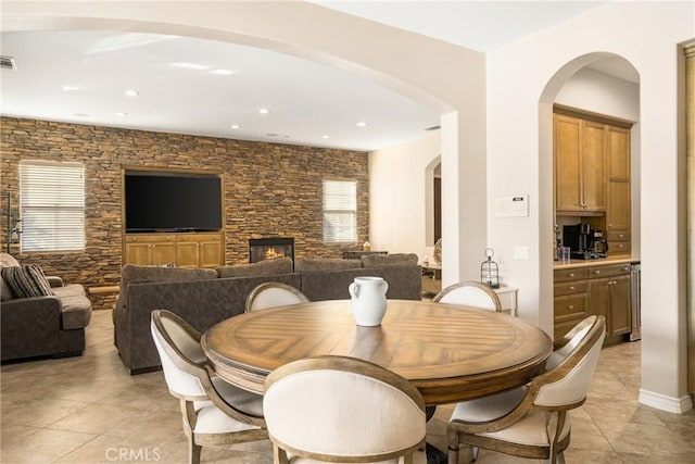 tiled dining room with a stone fireplace