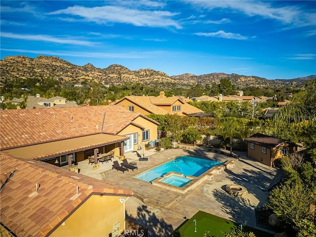 view of pool with an in ground hot tub, a storage shed, a mountain view, and a patio area