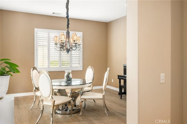 dining space with a notable chandelier and light wood-type flooring