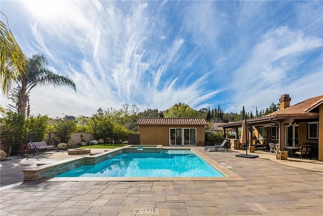 view of pool with an outdoor structure, a patio, and an in ground hot tub