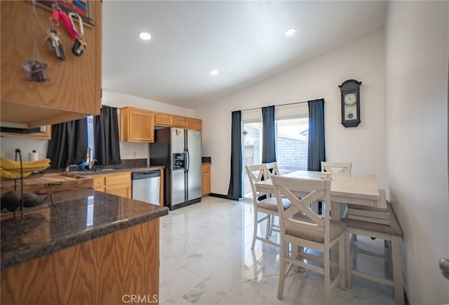 kitchen with lofted ceiling, stainless steel appliances, and dark stone countertops