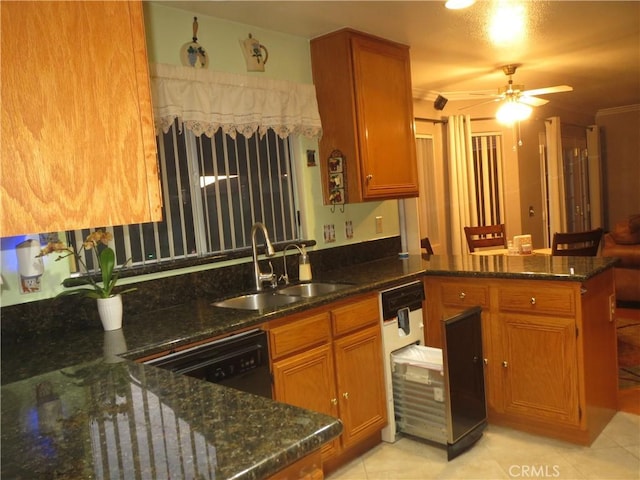 kitchen with brown cabinetry, dark stone countertops, a peninsula, and a sink