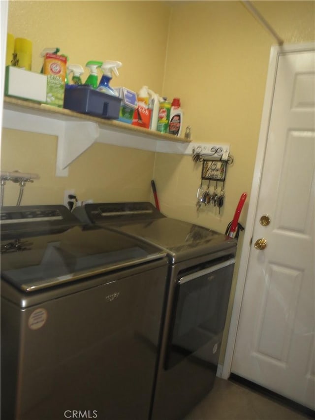 laundry area featuring tile patterned flooring, laundry area, and washing machine and clothes dryer