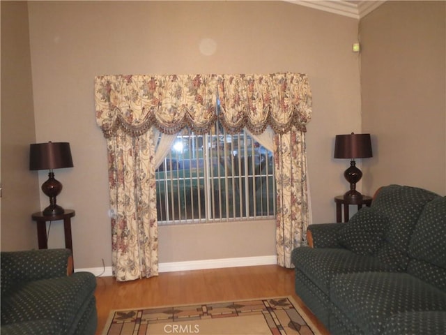 sitting room featuring ornamental molding, baseboards, and wood finished floors